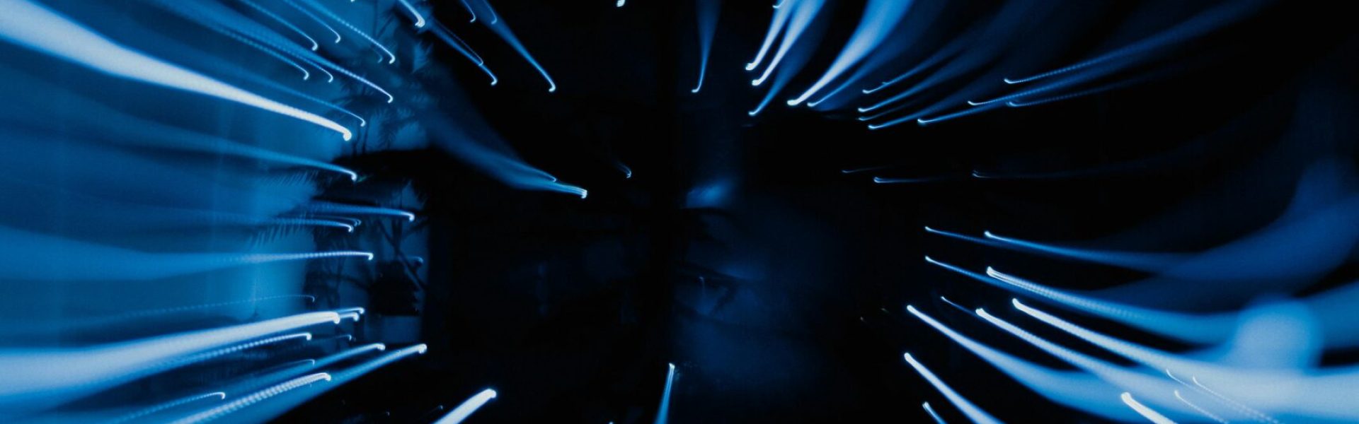 Dynamic abstract image showcasing blue light streaks captured in motion with a dark background.